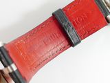 someone is holding a watch with a red strap on it