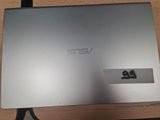 un ordinateur portable argenté posé sur un bureau en bois, à côté d'un clavier
