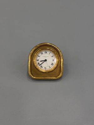 a gold clock on a gray surface with a white face
