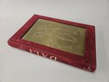 a red book with a gold cover sitting on top of a white table