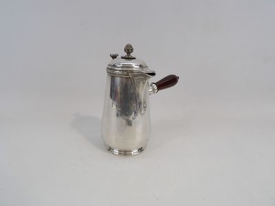 une cafetière en argent avec une poignée en bois sur une surface blanche