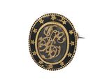 a close up of a gold and black ring with a monogram on it