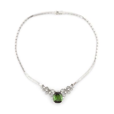 un gros plan d'un collier orné d'une pierre verte sur fond blanc