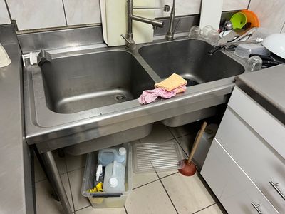 un évier en acier inoxydable dans une cuisine, à côté d'une cuisinière