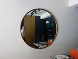 a round mirror on the wall above a desk