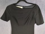 the back of a black dress on a hanger on a gray background