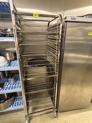 une étagère en acier inoxydable avec des casseroles et des poêles dans une cuisine