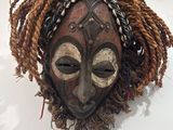 un masque en bois accroché au mur d'une pièce