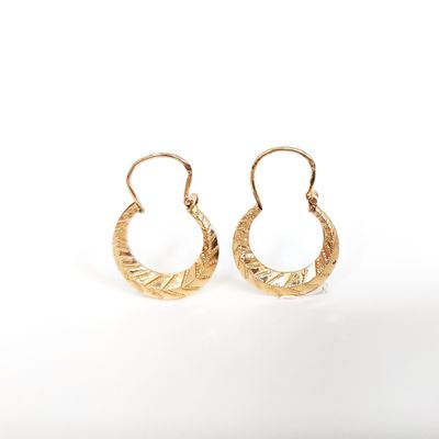 une paire de boucles d'oreilles en or sur fond blanc