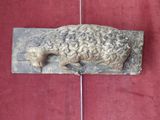 a stone sculpture of a sheep on a red surface