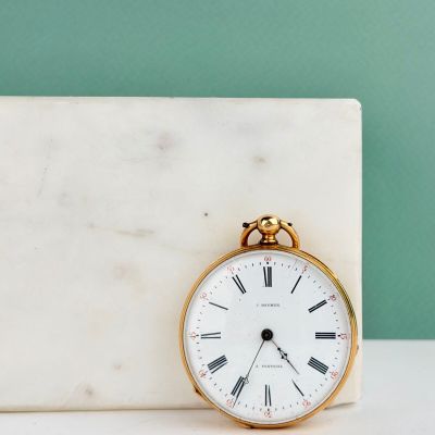 un bloc de marbre blanc sur lequel est posée une horloge dorée