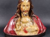 statue de Jésus tenant un cœur brisé sur fond noir