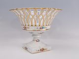 un vase blanc à bord doré, posé sur un socle