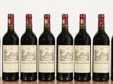 six bottles of red wine lined up on a wooden table