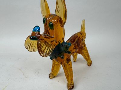 une figurine en verre représentant un chien tenant un oiseau dans la gueule