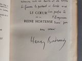 un livre ouvert, sur lequel est inscrit un poème manuscrit, posé sur une table