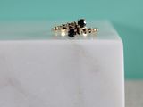 a close up of a black diamond ring on a white marble block