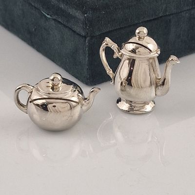 deux théières en argent posées l'une à côté de l'autre sur une table