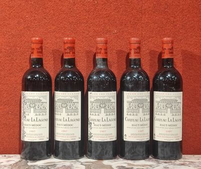 six bouteilles de vin rouge alignées sur une table devant un mur rouge