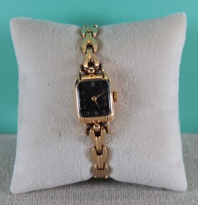 an image of a gold watch sitting on top of a pillow