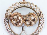 an image of a gold pendant with three flowers inside of it