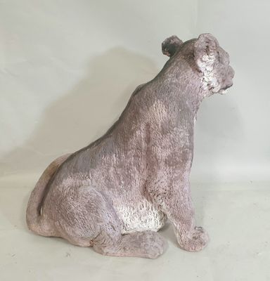 une statue représentant un chien assis sur une surface blanche