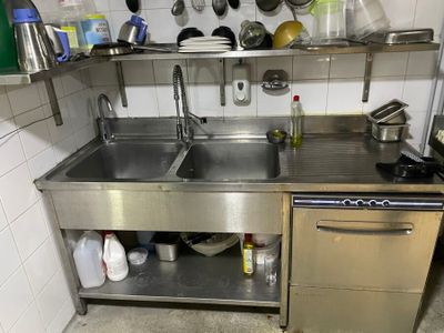 a stainless steel sink in a kitchen with pots and pans hanging on the wall