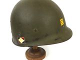 an army helmet on a wooden stand on a white background