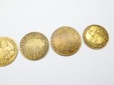 quatre pièces d'or sont disposées en ligne sur une surface blanche
