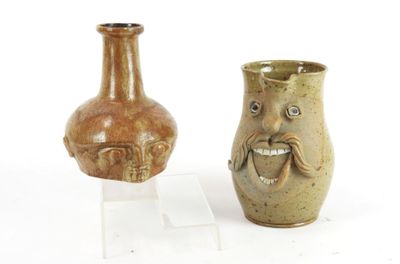 two vases with faces on them sitting on a stand