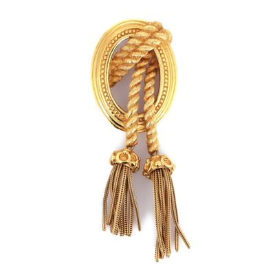 un gros plan d'une broche en or ornée de pompons, sur fond blanc