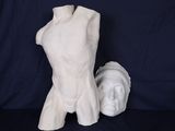 une sculpture blanche représentant un torse et une tête, posée sur une table