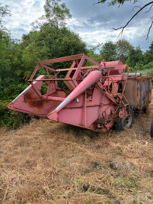un tracteur garé dans l'herbe près d'une moissonneuse-batteuse rose