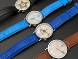 three different colored watches are sitting next to each other on a black surface