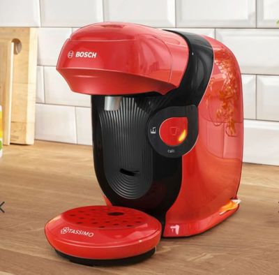 the red coffee maker is sitting on the counter next to a glass of orange juice