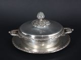 an antique silver plate with a lid and a flower decoration