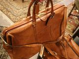 a person holding a brown leather bag in their hand