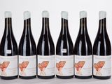 six bottles of wine are lined up in a row on a white surface