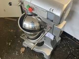 a silver mixer sitting on the floor next to a white wall