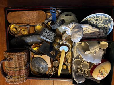 une boîte noire remplie d'objets divers posée sur une table en bois