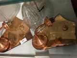 a glass shelf with a pair of antique brass lamps on it
