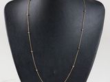 a black mannequin necklace with gold beads on a black mannequin