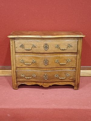 une petite commode en bois posée sur un sol recouvert de moquette