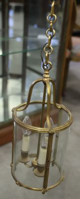a glass and brass hanging light fixture in a room