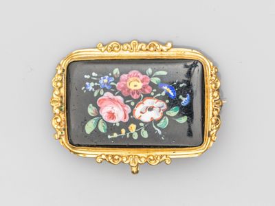 un gros plan sur une broche noire et dorée ornée de fleurs