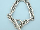 a close up of a chain bracelet with a clasp on a blue surface
