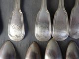 six silver spoons are lined up in a row on a table
