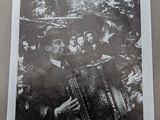 black and white photograph of a man playing an accordion in front of a group of people