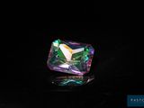 a close up of a colorful crystal stone on a black surface