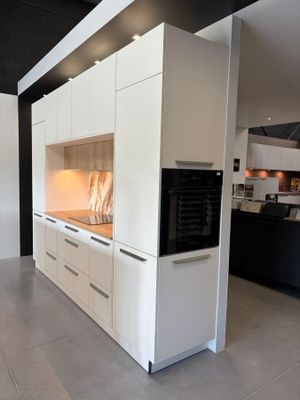 une grande cuisine avec des placards blancs et des plans de travail noirs